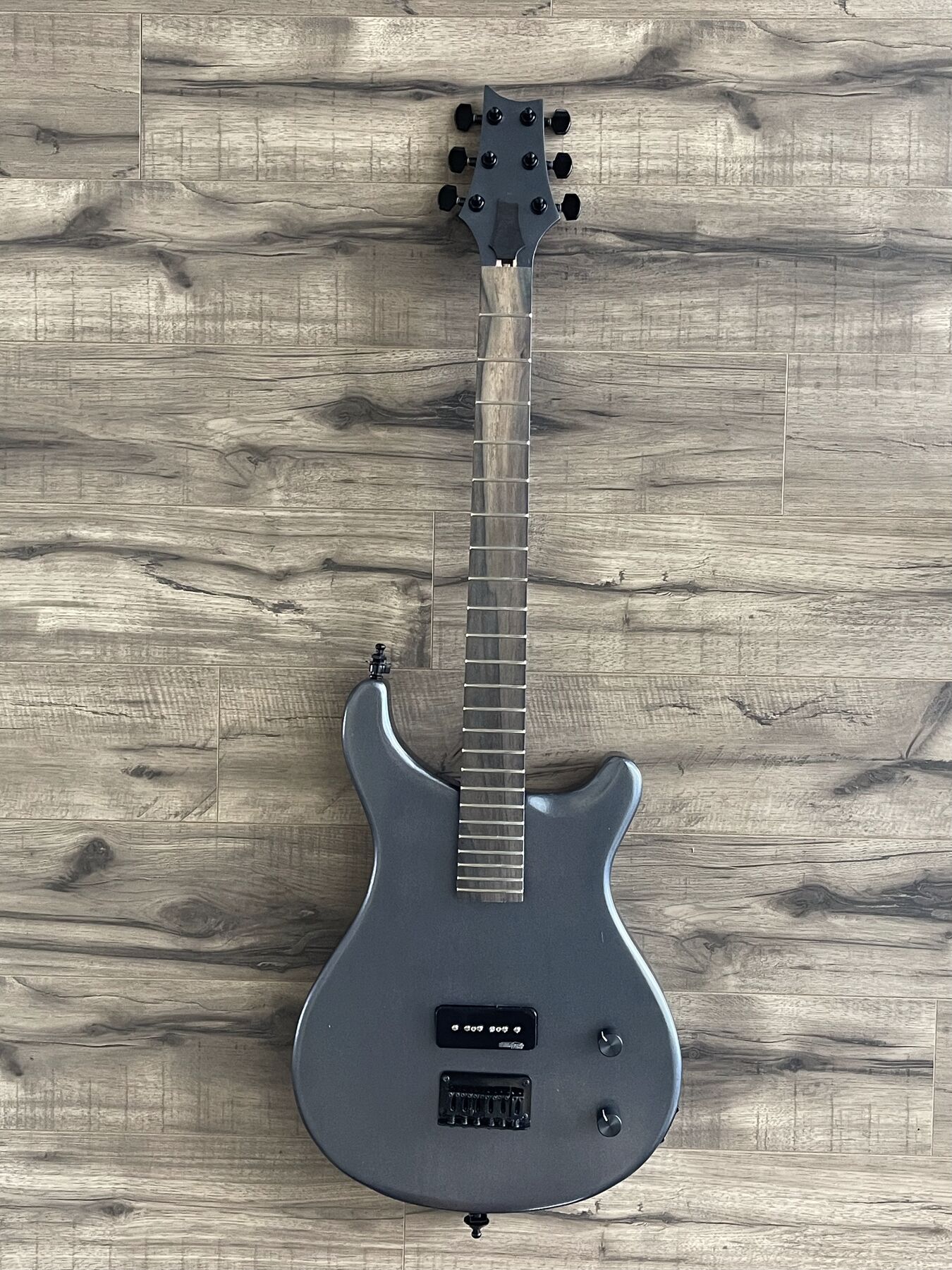 Gunmetal grey double-cutaway guitar with one black P90 pickup and a black headstock