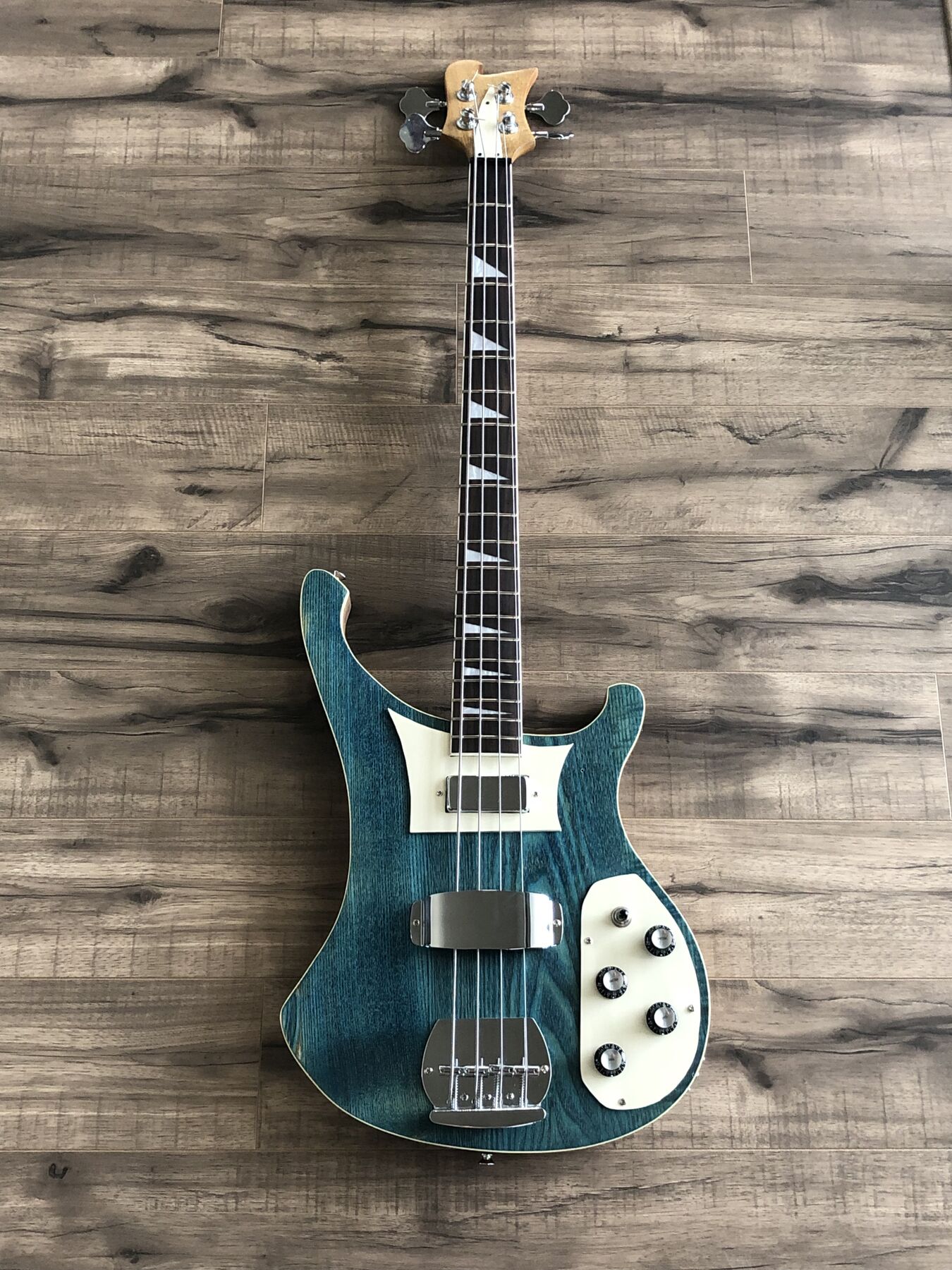 Teal-stained four-string bass with cream pickguards and triangle inlays