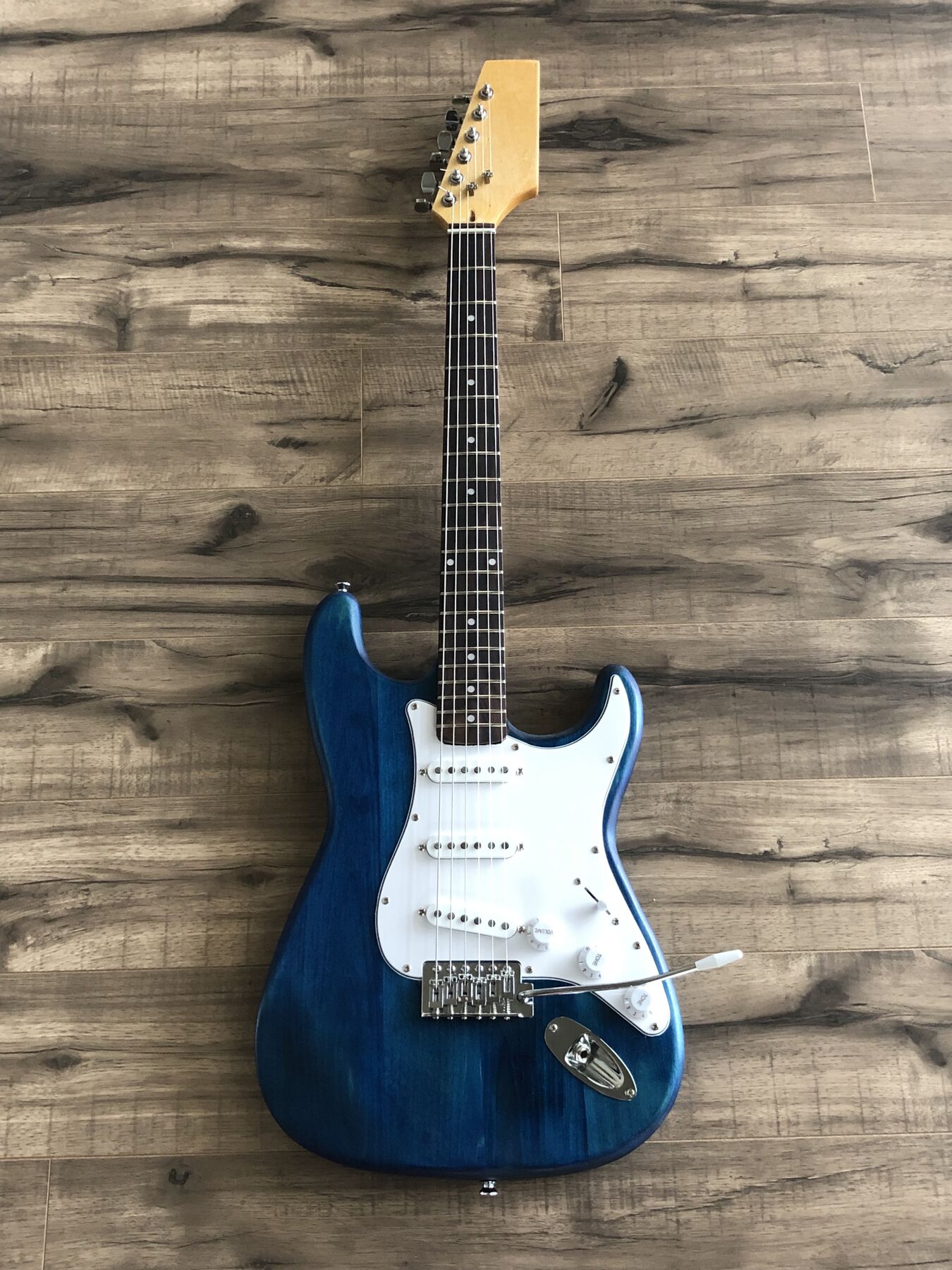 Blue-stained double-cutaway guitar with a white pickguard and three single-coil pickups