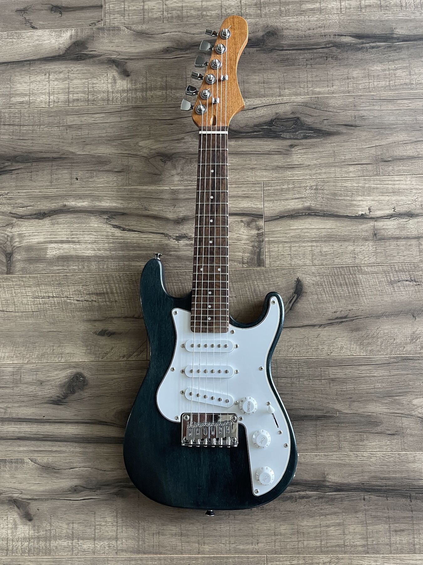 Small-bodied double-cutaway guitar in a dark blue stain with a white pickguard and three single-coil pickups