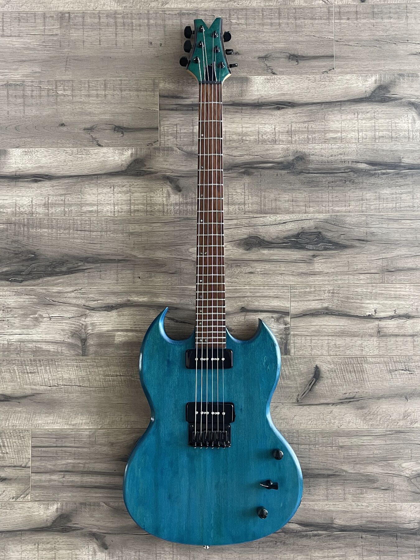 Aqua-stained double-cutaway guitar with black hardware and two black P90 pickups