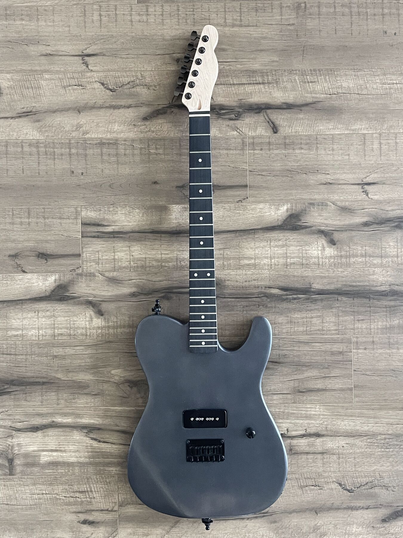 Gunmetal grey single-cutaway guitar with one black P90 pickup and a maple headstock
